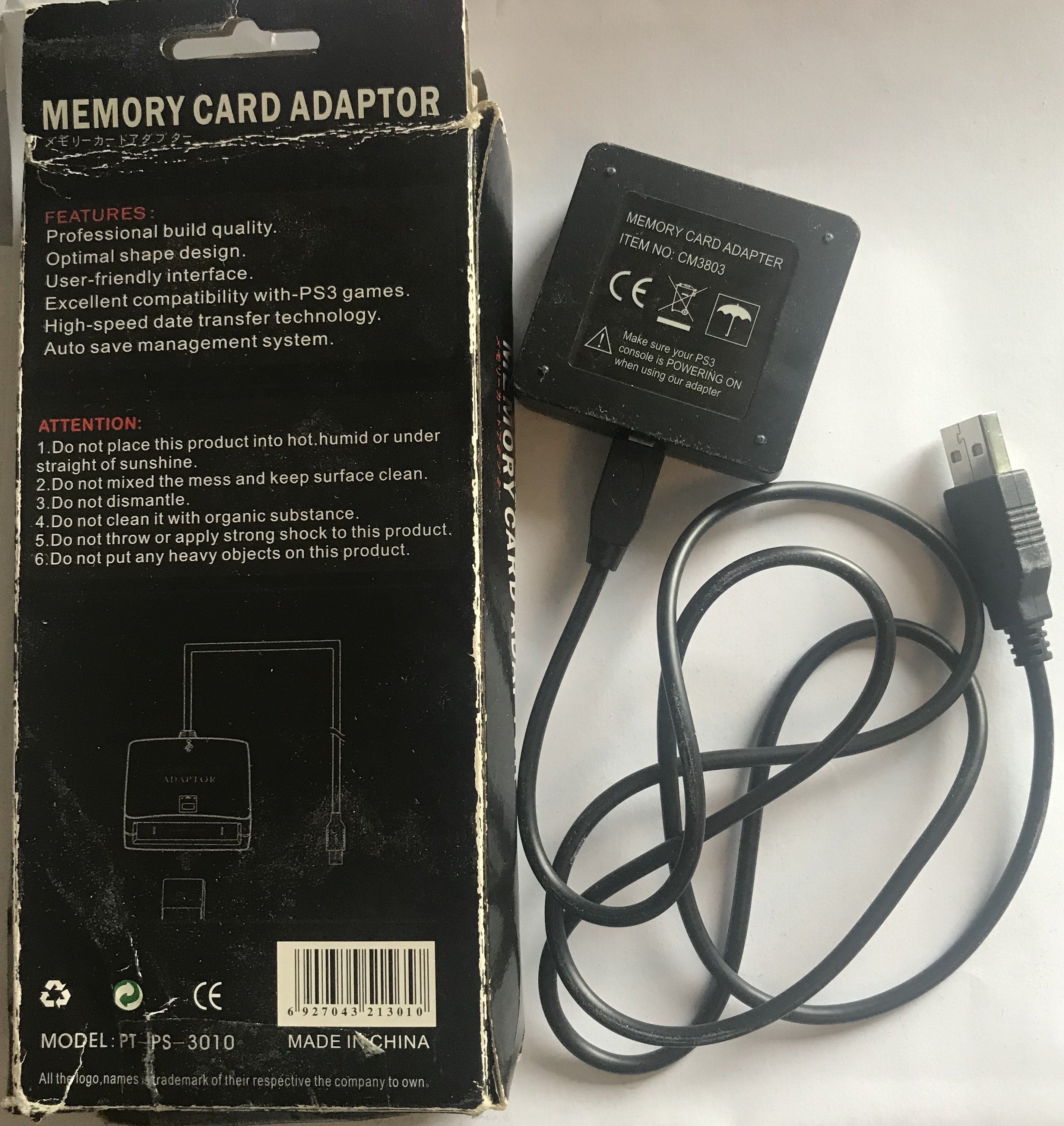 photo of the back of the packaging for a ”Memory Card Adaptor” and the device itself, which is a small black box connected to a USB cable