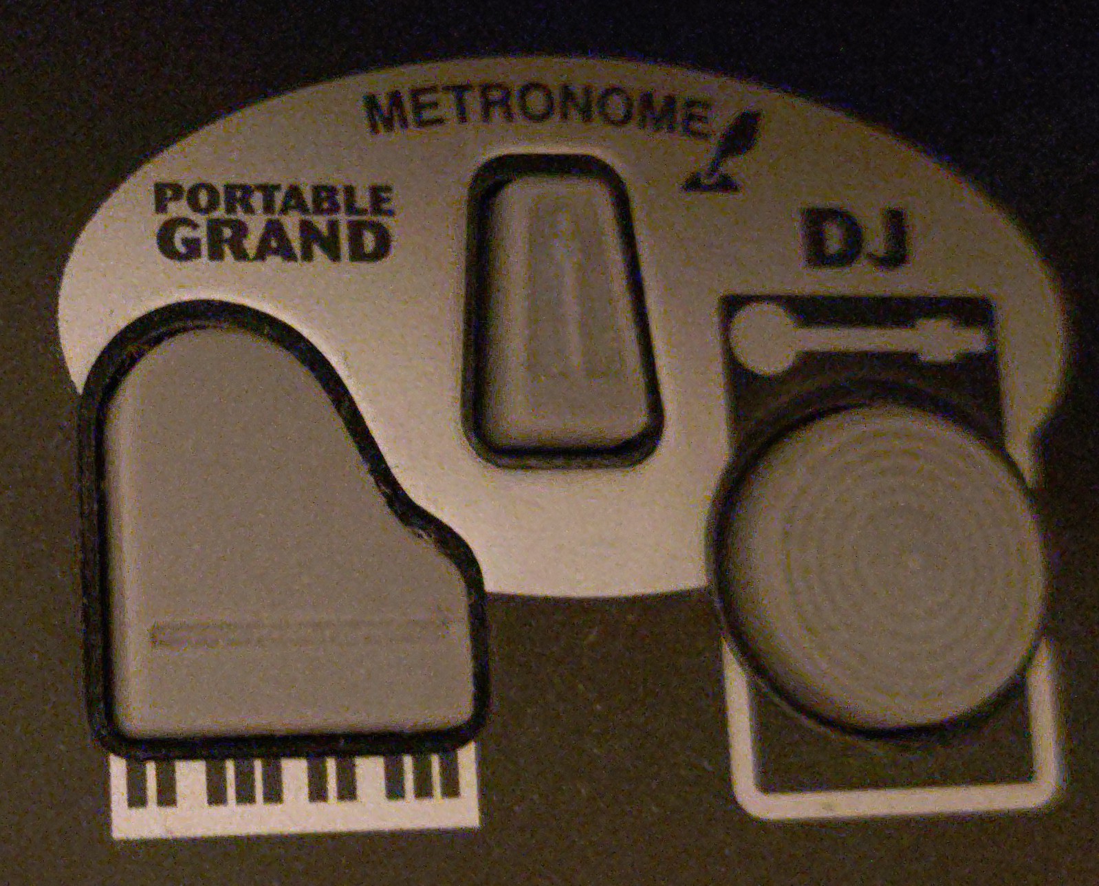 Close-up photo of the zone on the PSR-350's controls panel which features the “Portable Grand”, “Metronome” and “DJ” buttons, all made of grey rubber. The “Portable Grand” button is shaped like the profile of a grand piano viewed from a top-down perspective, with a simplified illustration of a keyboard being printed on the plastic below it. Similarly, the “DJ” button is shaped like a platter on a record player (complete with grooves), with a tone arm printed on the plastic above it. The metronome button looks like a metronome.